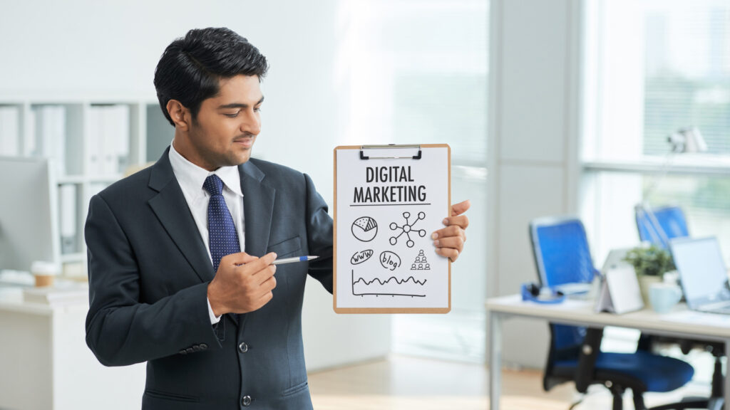 rayan ict- SEO marketing service provider company-Power of Digital Marketing- man wearing a black suit holding a paper with digital marketing text on it in the office